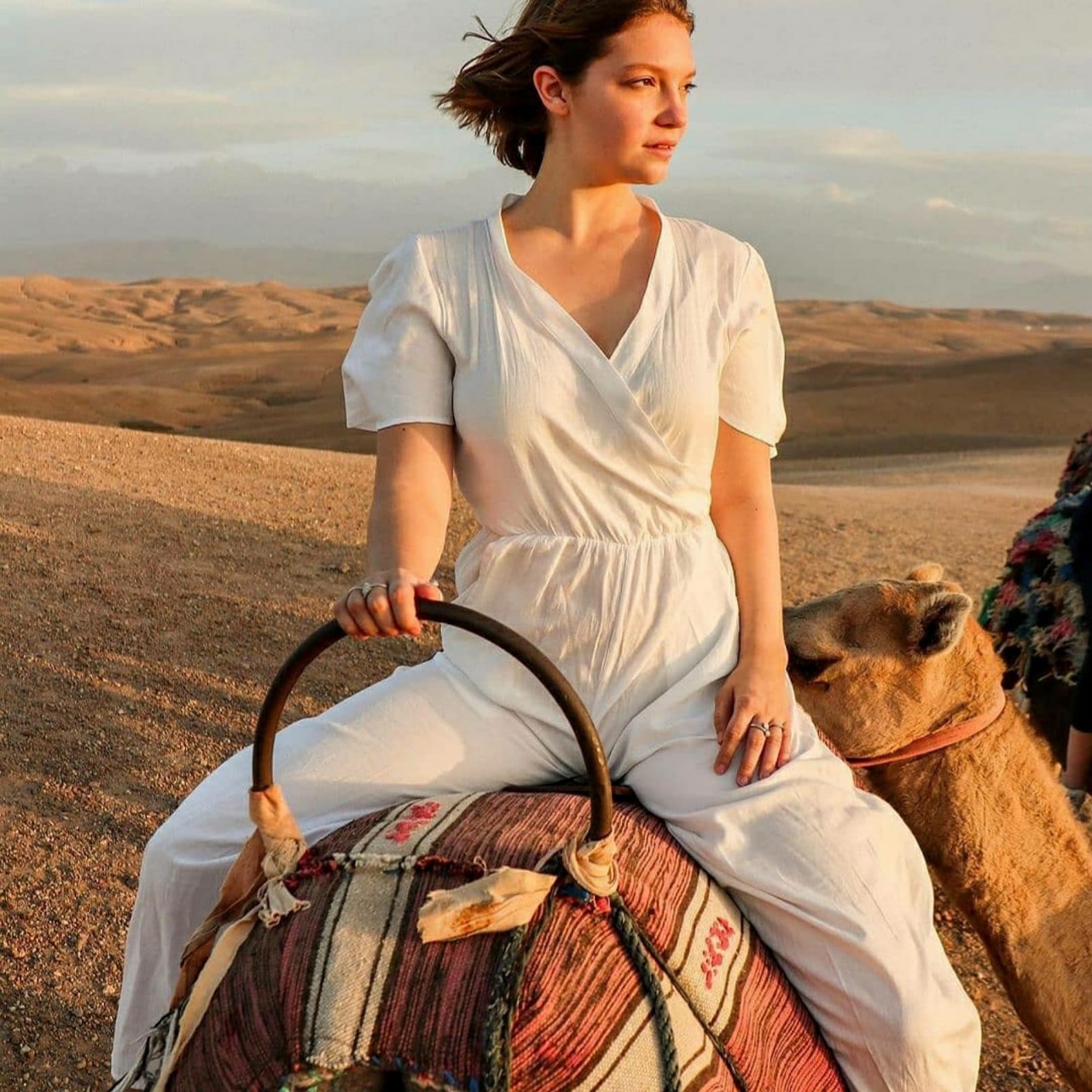 A traveller riding a camel across the Agafay stone desert in golden evening light